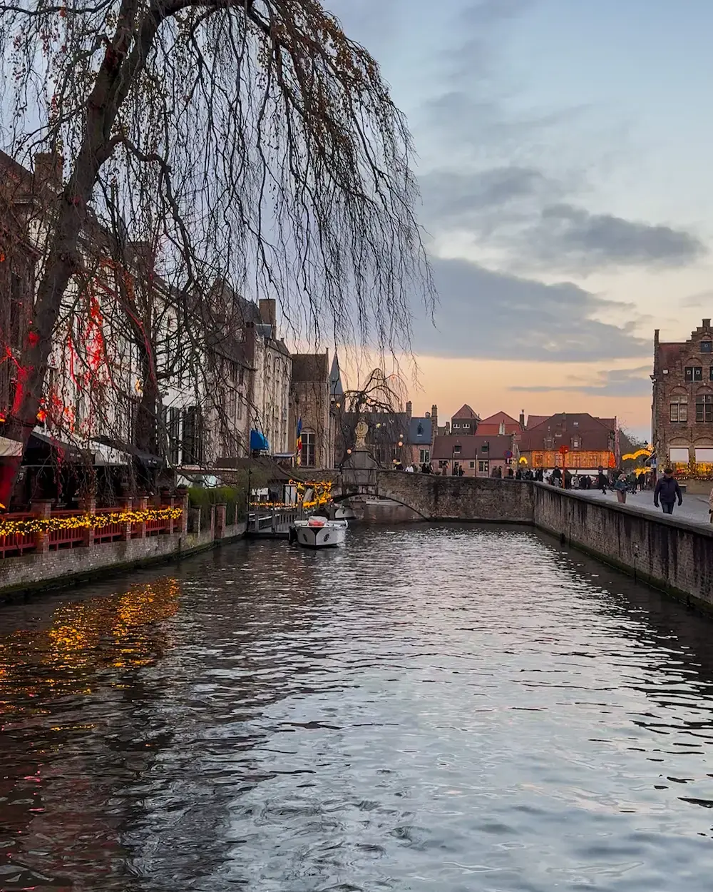 Canal boat tour passing under a bridge in Bruges